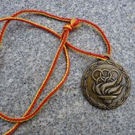 Medaille mit dem olympischen Feuer und Olympia Ringen