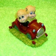 Niedliches Kinderpärchen fährt im Auto aus Kunststein handbemalt