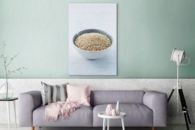 Leinwandbilder - 80x120 cm - Eine Porzellanschale voller Quinoa-Körner auf einem weiß