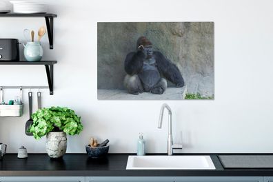 Leinwandbilder - 60x40 cm - Ein riesiger Gorilla lehnt an einer Steinmauer