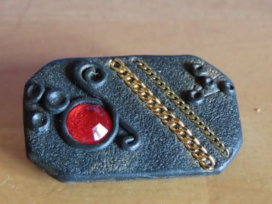 Brosche schwarz mit rotem Stein + zwei goldfarbenen Kettenstücke FIMO?